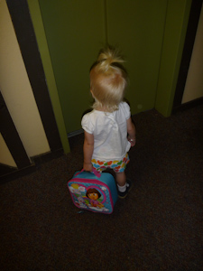 Waiting patiently for the elevator with her lunchbox