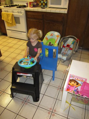 Front view of Adria in her "car" in the kitchen